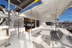 Ein Bootsdeck mit Sitzgelegenheiten, Tischen und einem überdachten Bereich mit Fenstern.