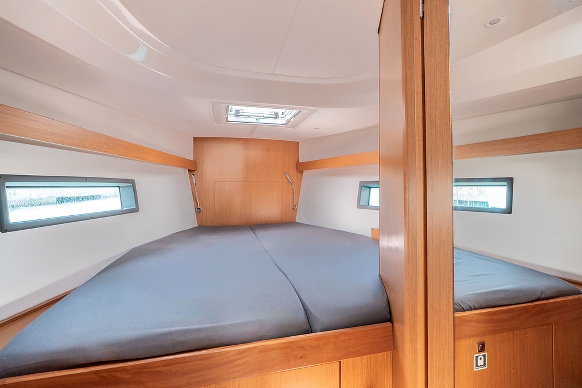 A compact interior with a bed, two windows, and a skylight.