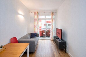 A modern living room with a grey sofa, a wooden table, and a TV on a stand. - GuestReady - Rosamar 304 P (Las Palmas de Gran Canaria)