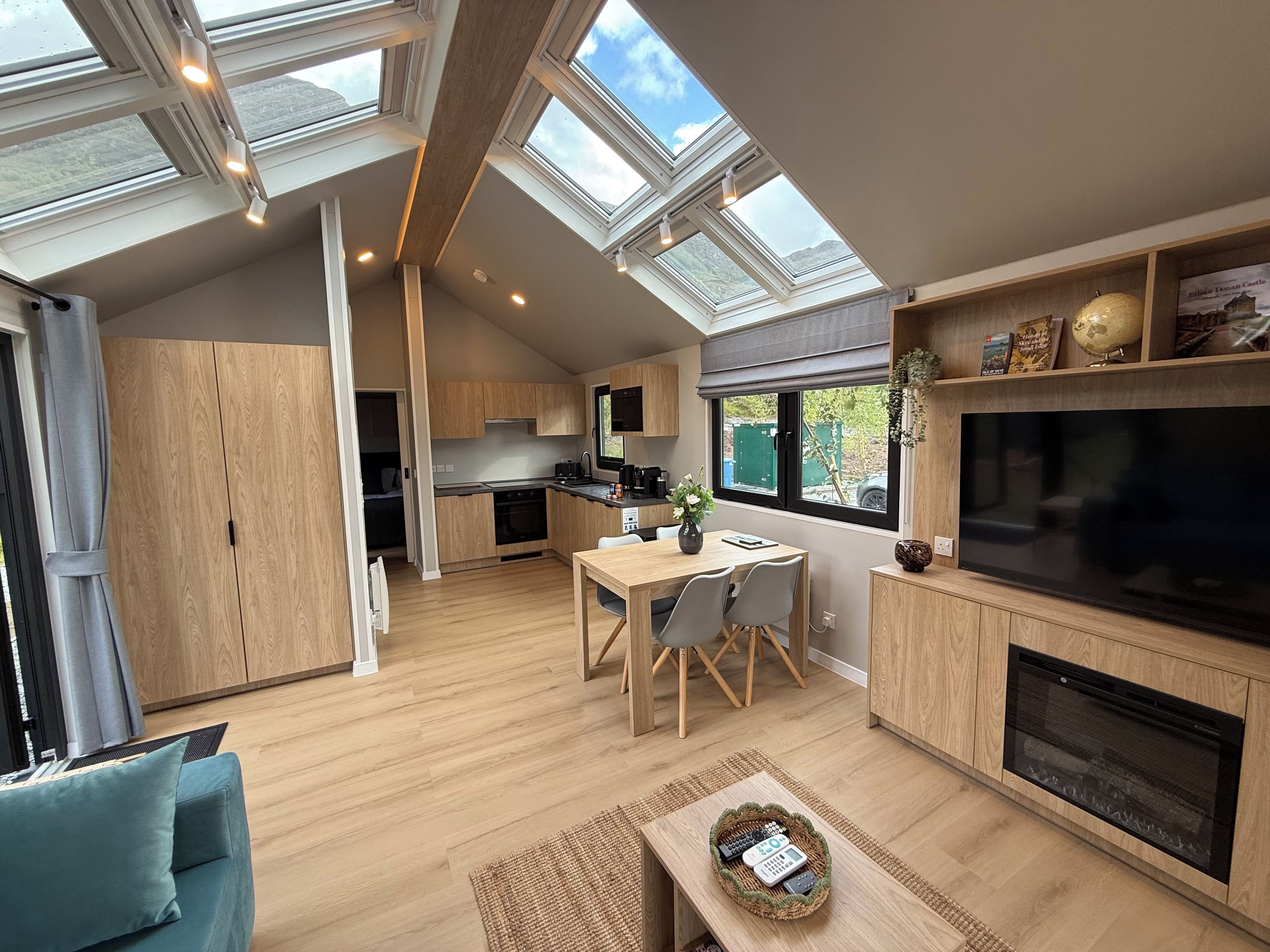 A modern kitchen with skylights, a dining area with a TV, and a cozy seating area.