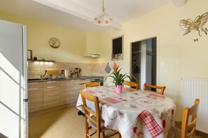 A kitchen with a dining table, chairs, a clock, and a potted plant.