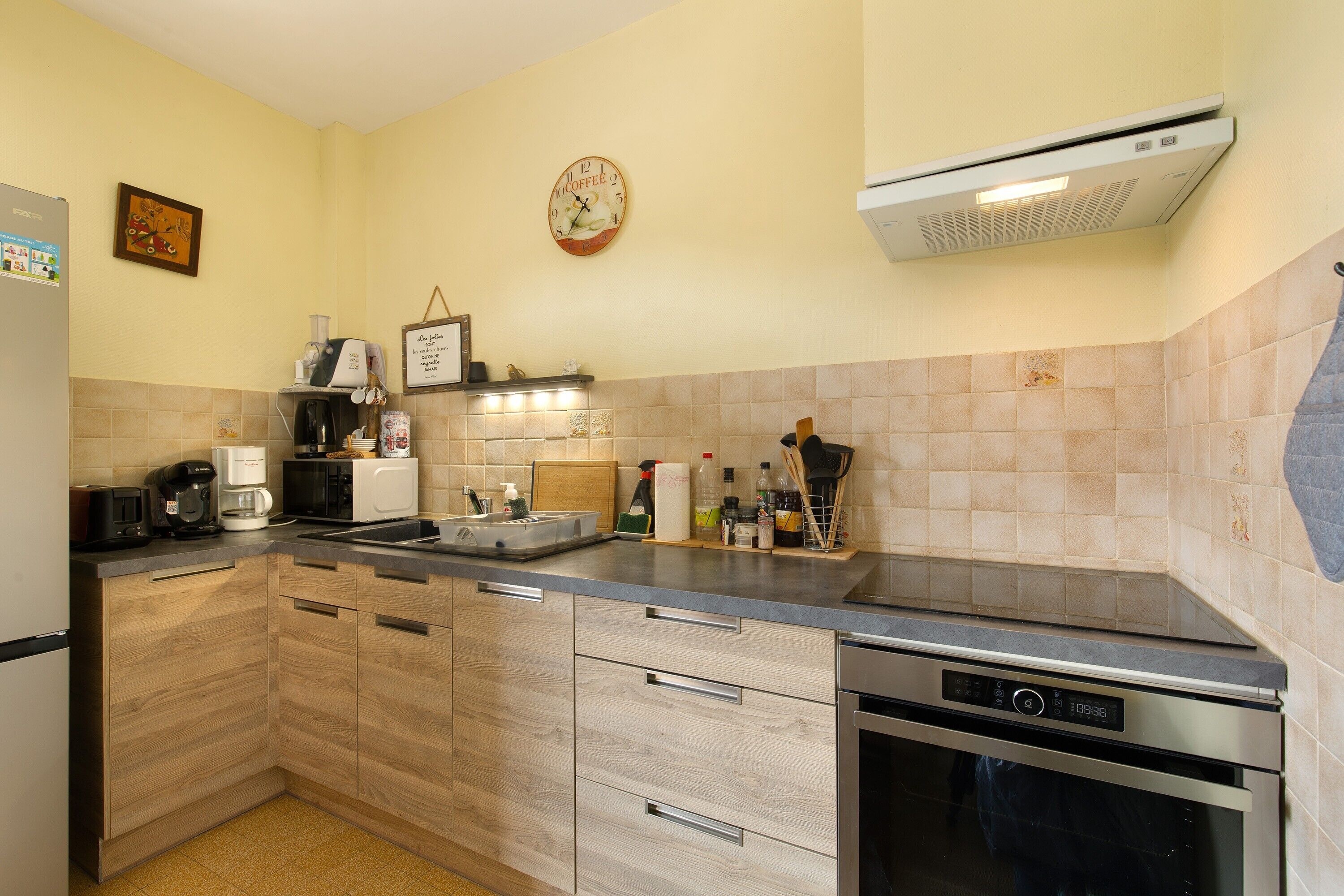 A kitchen with a built-in dishwasher, a coffee machine, and a microwave.