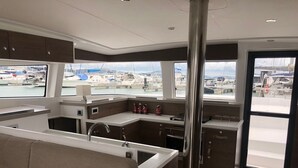 Una cucina funzionale con lavello, fornelli e pensili, un'area salotto con sedute imbottite e ampie finestre che si affacciano su un porto turistico.
