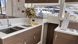 Una cucina compatta con lavello, pensili in legno e un vaso con fiori.