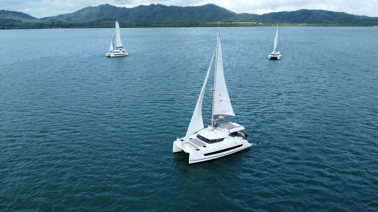 Una barca a vela su acque calme, con montagne sullo sfondo.