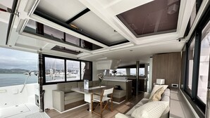 Un interno moderno con zona pranzo, divano e ampie finestre con vista sull'acqua.