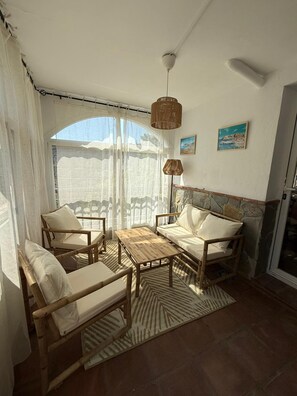 Ein Balkon mit Korbmöbeln, einem gemusterten Teppich und einer Steinwand.