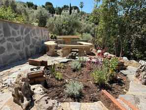 Ein Garten mit Stebänken, einer Steinmauer und verschiedenen Pflanzen.