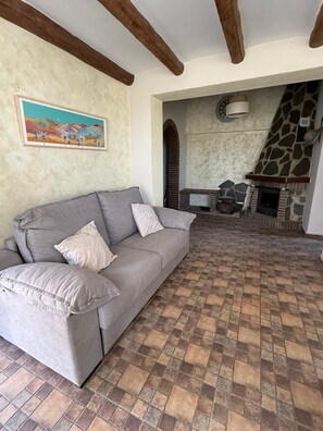 A living room with a grey sofa, a fireplace, and a tiled floor. - Casa Meraki by R&R in Competa with a private pool. (Cómpeta)