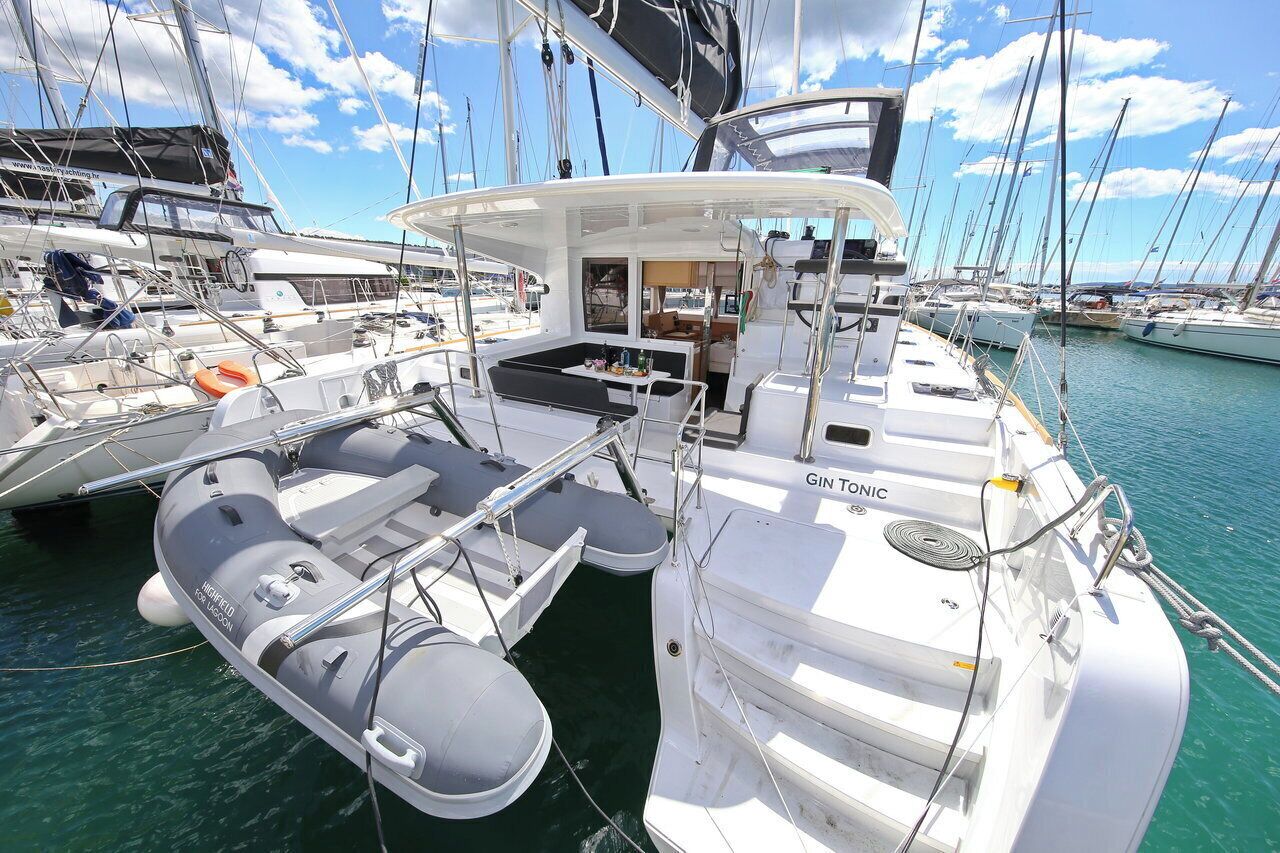 Un port de plaisance où est amarré un bateau appelé « GIN TONIC », avec un espace de repos abrité, une petite table et une bouée de sauvetage.