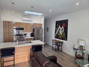 A modern kitchen with a central island, stainless steel appliances, and wooden cabinets. - Stylish pet-friendly 1-bedroom home on the border of Kelowna/Lake Country (Kelowna)