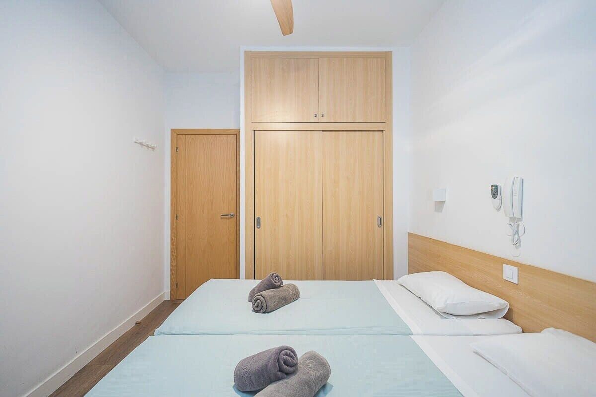 Habitación de hotel con dos camas, armario de madera y teléfono en la pared.