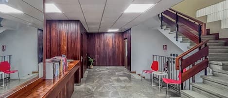 A reception area with a wooden reception desk, a staircase, and a tiled floor.