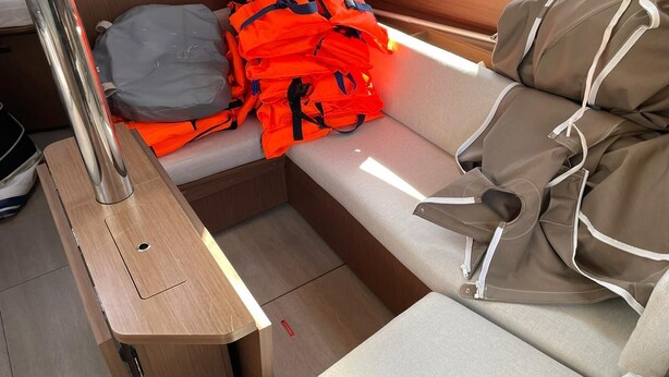 Ein gemütlicher Innenraum mit einer hölzernen Bank, einem kleinen Tisch und einem Stapel orangefarbener Rettungswesten.
