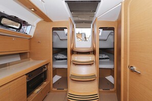 Un intérieur de camping-car compact comprenant un coin cuisine, deux espaces nuit et une petite table.
