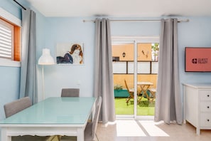 Ein modernes Hotelzimmer mit einem Glastisch, einer Couch, einem Gemälde, einer Schiebetür zum Garten und einem Schild mit der Aufschrift 'GUEST READY'.