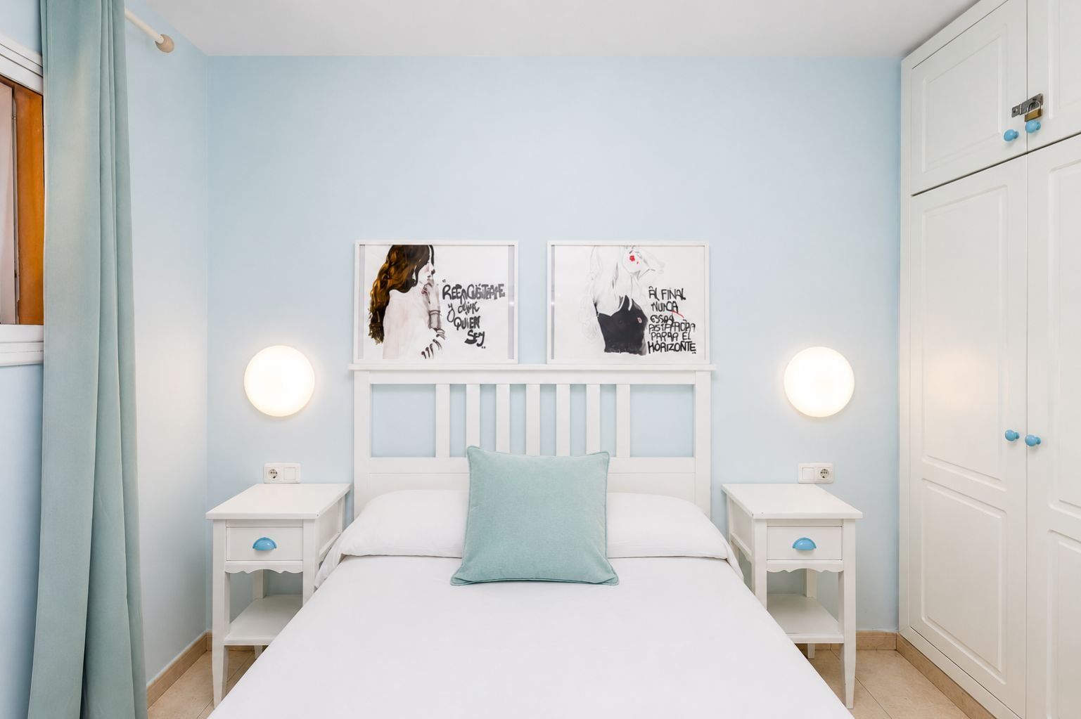 Une chambre à coucher comprenant un lit, deux tables de chevet, une armoire et deux appliques murales.