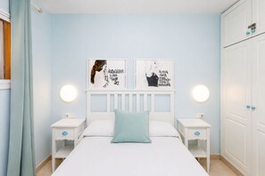 Ein Schlafzimmer mit einem Bett, zwei Nachttischen, einem Kleiderschrank und zwei Wandleuchten.