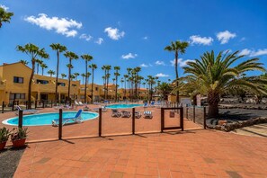 Ein Resort mit mehreren Swimmingpools, Palmen und blauem Himmel.