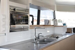 A modern kitchen with a stainless steel sink, a built-in oven, and a window overlooking a cityscape. - Sun-Kissed Sailing Adventure in Zadar, Croatia (Biograd na moru)