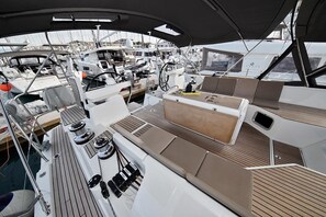 A marina with multiple boats docked, a covered deck area with seating, and a view of the marina in the background. - Sun-kissed Sailing Adventure in Split-Dalmatia, Croatia (Trogir)