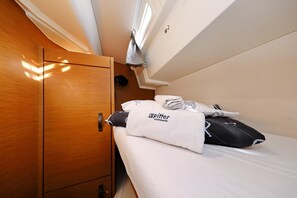 A compact cabin with a wooden wardrobe, a bed with neatly folded towels, and a small window. - Sun-kissed Sailing Adventure in Split-Dalmatia, Croatia (Trogir)