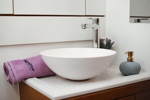 Ein Badezimmer mit einem weißen Waschbecken, einem violetten Handtuch und einem Seifenspender.