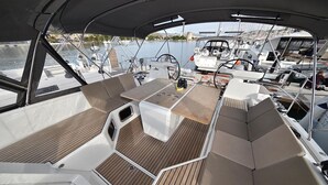 A boat deck with a central table, cushioned seating, and a view of the marina. - Sun-kissed Sailing Adventure in Split-Dalmatia, Croatia (Trogir)