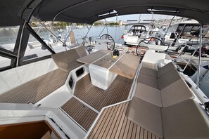 Ein Bootsdeck mit einem zentralen Tisch, gepolsterten Sitzgelegenheiten und Blick auf den Hafen.
