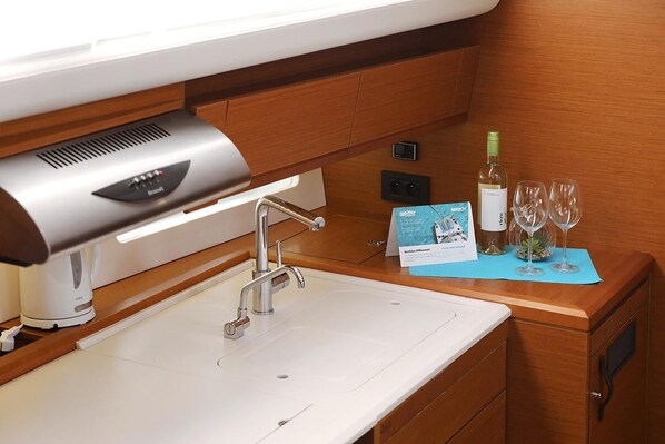 A modern kitchen area with a built-in coffee machine, a stainless steel sink, and a wine bottle on the counter. - Sun-kissed Sailing Adventure in Split-Dalmatia, Croatia (Trogir)
