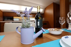 Ein Esstisch mit einer Weinflasche, einem Topf Lavendel und einer Schüssel Essen.