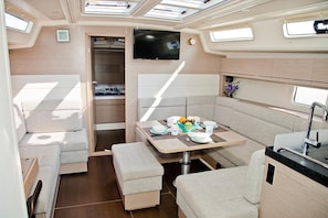 A compact RV interior with a dining area, a TV mounted on the wall, and a kitchenette. - Sun-Kissed Sailing Adventure in Istria, Croatia (Pula)