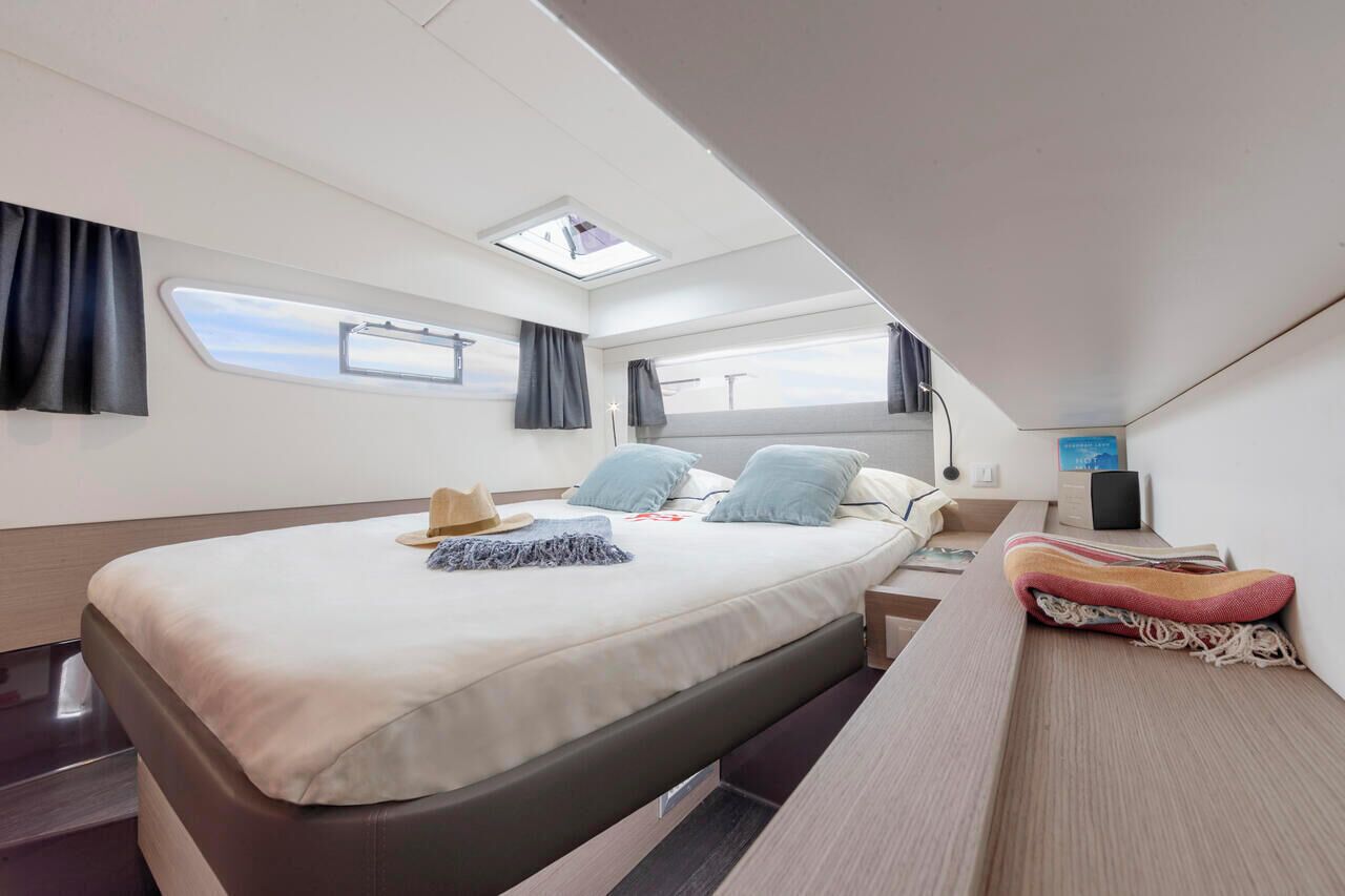 Een moderne slaapkamer met een bed, dakraam, nachtkastje, televisie en raam.