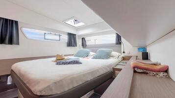 Een moderne slaapkamer met een bed, dakraam, nachtkastje, televisie en raam.
