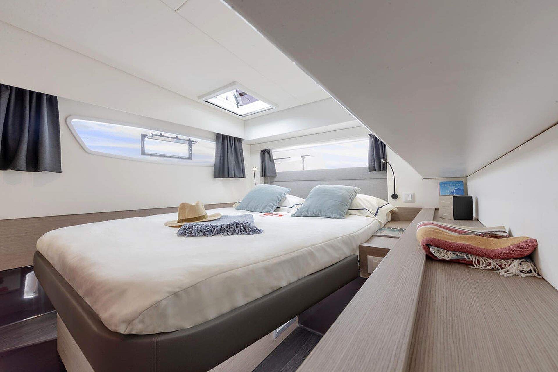 A modern, well-lit bedroom with a large bed, a desk, and a skylight.