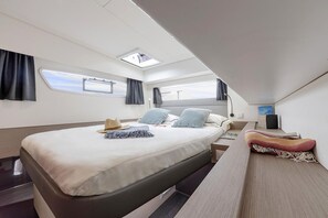 A modern, well-lit bedroom with a large bed, a desk, and a skylight.