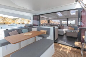 A modern yacht interior with a dining area, seating, and a view of the sea. - Caribbean Sun-Kissed Sailing: A Luxurious Beach Experience from Martinica, Le Marin (Le Marin)