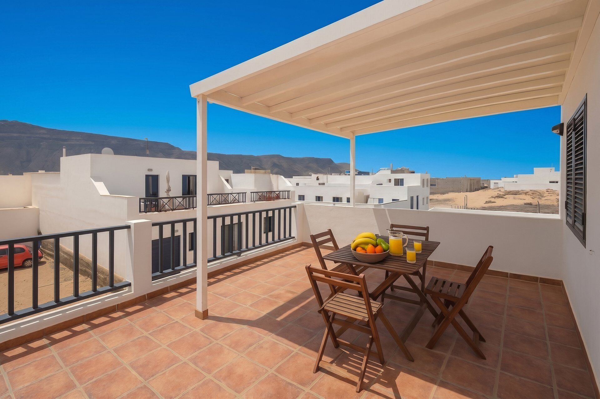 A terrace with a table set for breakfast, a view of the city, and a white building in the background.