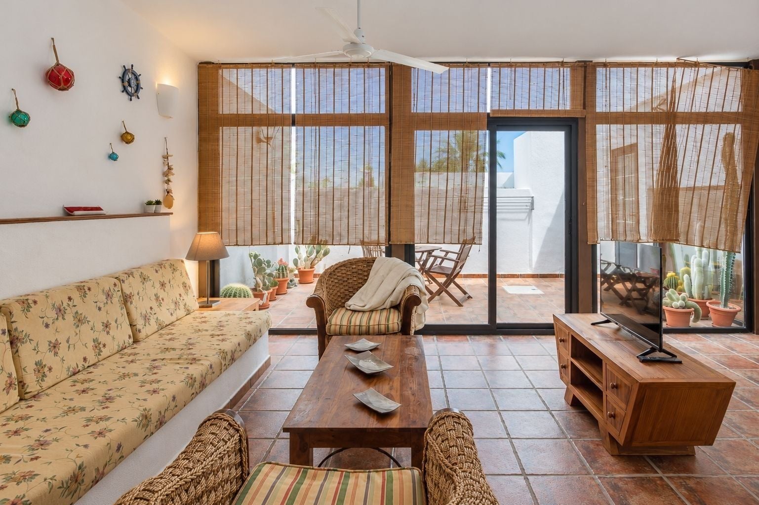A living room with a sofa, a coffee table, a wicker chair, and a television.
