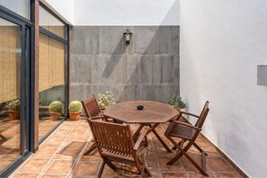 A patio with a round table and chairs, surrounded by potted plants and a wall-mounted light fixture. - GuestReady - La Graciosa Natural Paradise (Caleta de Sebo)