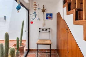 A room with a chair, a wooden cabinet, and a cactus collection. - GuestReady - La Graciosa Natural Paradise (Caleta de Sebo)