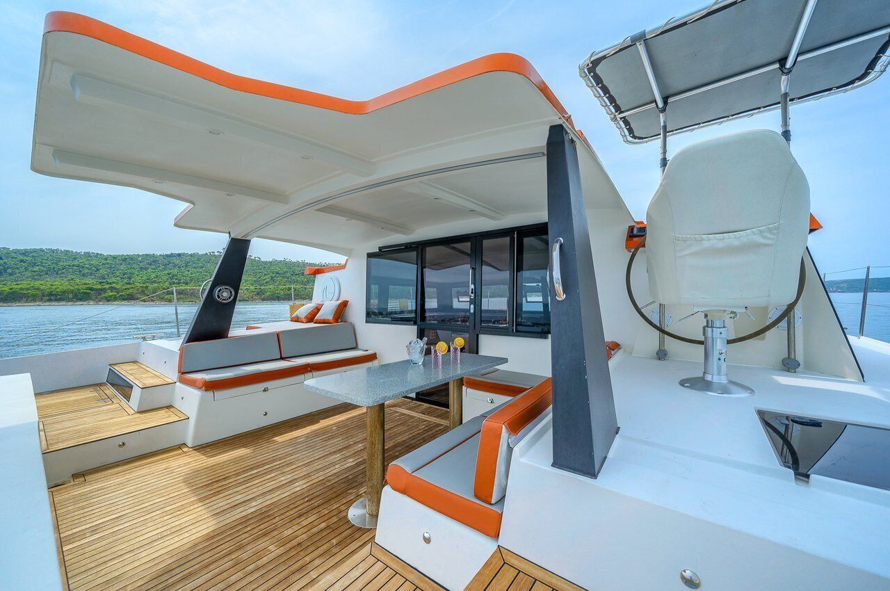 A boat deck with seating, a table, and a steering wheel.