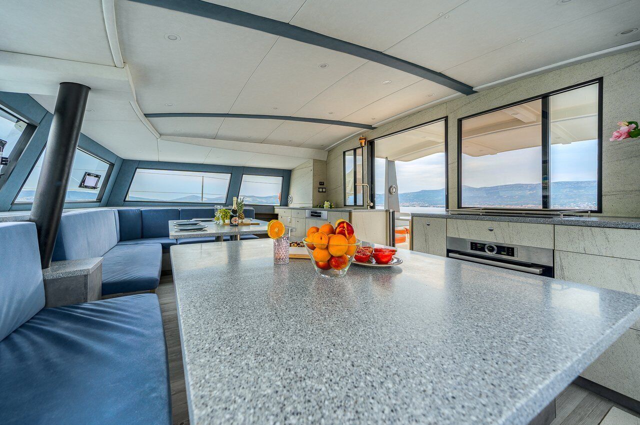 A modern kitchen with a central island, seating area, and large windows offering a view.