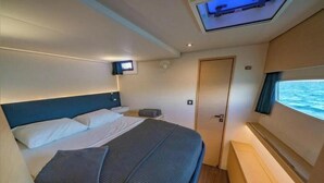 Ein Schlafzimmer mit Bett, Nachttisch, Fernseher und Fenster mit Meerblick.