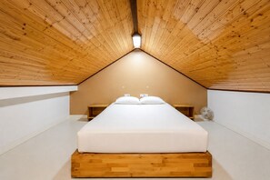 A bedroom with a sloped ceiling, a bed, bedside tables, and a fan. - GuestReady - Bright Retreat with Outdoor Pool (Corralejo)
