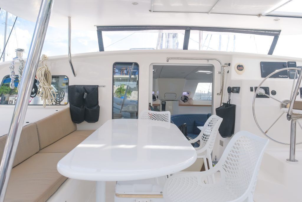 Le pont d’un bateau, avec une table et des chaises, un volant et un petit coin salon.