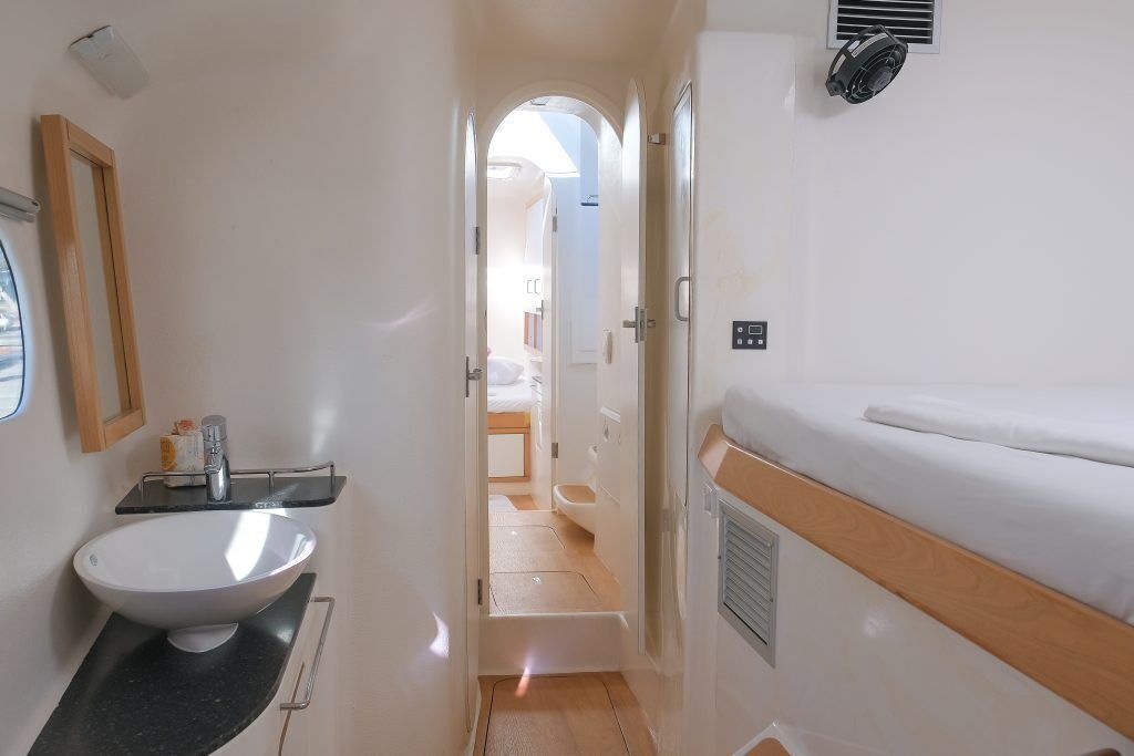 Une salle de bain compacte pour camping-car, avec un lavabo blanc, un miroir et un espace douche.