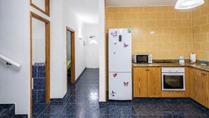 Eine Küche mit Kühlschrank, Mikrowelle, Backofen und Holzschränken.