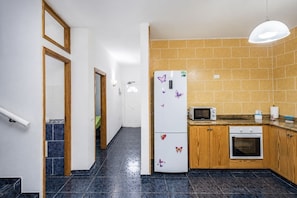 Eine Küche mit Kühlschrank, Mikrowelle, Backofen und Holzschränken.