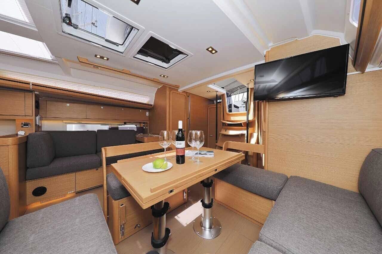 En kompakt autocamper indretning med spiseplads, siddepladser, et fladskærms-tv og et tekøkken.